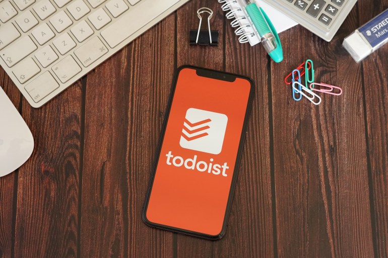 barcelona, spain - june 11, 2020; todoist app with stationery on a brown wooden table. todoist is app to manage tasks and projects anywhere. todoist