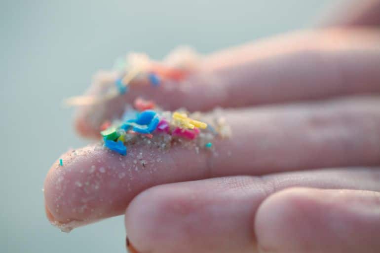 Researcher holding small pieces of micro plastic pollution washed up on a beach - stock photo