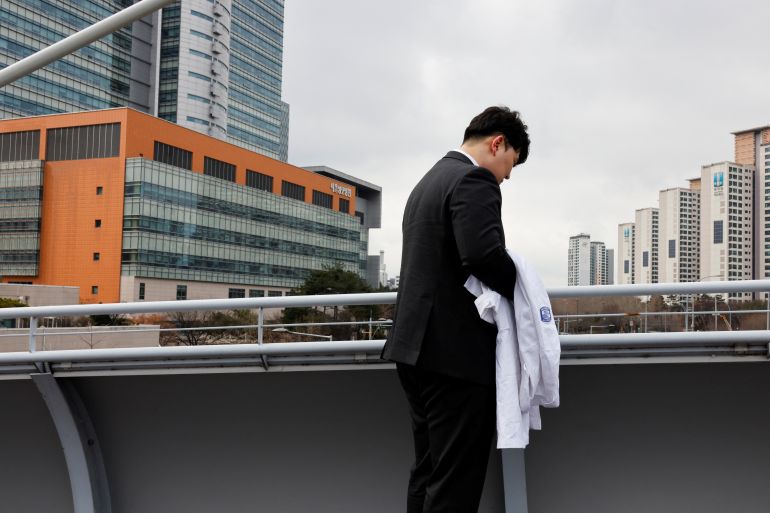 Ryu O. Hada, 25, one of the thousands of South Korean trainee doctors who resigned en masse to protest the government's medical policy, holds his white coat in front of the hospital where he worked in Seoul, South Korea, February 25, 2024. REUTERS/Kim Soo-Hyeon