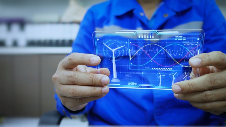 engineer is checking the power parameters real time status of a wind turbine generator through ai hologram screen. artificial intelligence, helps in analyzing and solving energy problems. green energy