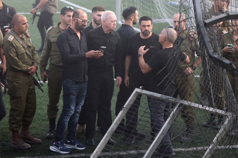 Israeli Minister of Defense Yoav Gallant (C) visits the site where a reported strike from Lebanon fell in Majdal Shams village in the Israeli-annexed Golan area on July 28, 2024. - Israel's military said Hezbollah fired the rocket from Lebanon, hitting a football pitch in the Druze town of Majdal Shams and killing the youngsters, who were between 10 and 20 years old. Another 18 youths were wounded in the attack, said the emergency services. (Photo by Menahem KAHANA / AFP)