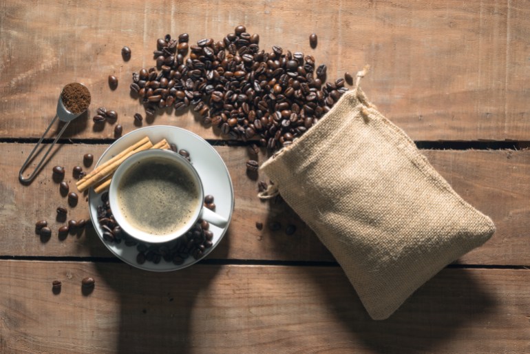 Top view of a coffee cup next to a bag of coffee beans.