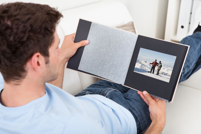 young man sitting on couch looking at photo album