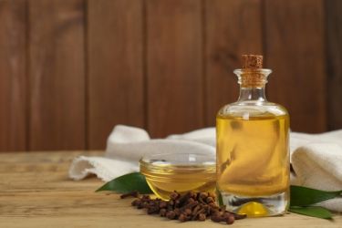 essential oil and dried cloves on wooden table. space for text شترستوك