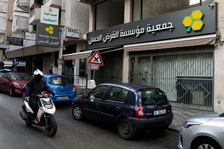 a man on a scooter passes a branch of the hezbollah-run qard al-hassan association, in beirut, lebanon, wednesday, jan. 20, 2021. as more lebanese fall into poverty in the country's economic crisis, increasing numbers are turning to the financial arm of the iranian-backed hezbollah militant group for help. qard al-hassan provides small, interest-free loans in dollars at a time when lebanese are desperate for hard currency and commercial banks are not lending. those seeking a loan must put up gold as collateral or bring in a guarantor and can receive a loan of up to $5,000. (ap photo/bilal hussein)