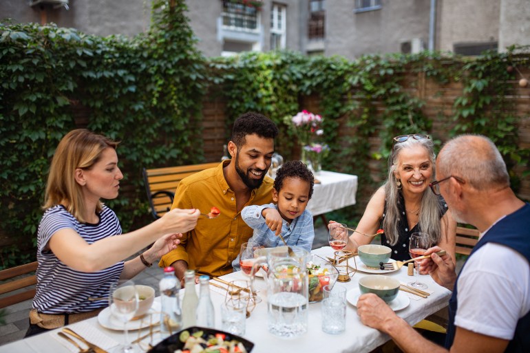 happy multigeneration family talking and laughing at garden during birthday party.