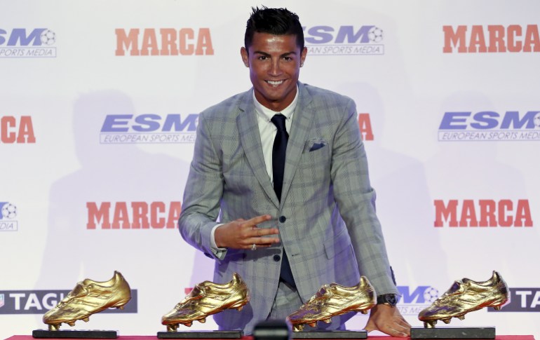 real madrid's striker cristiano ronaldo poses in front of his four golden boot trophies during a ceremony in madrid, spain