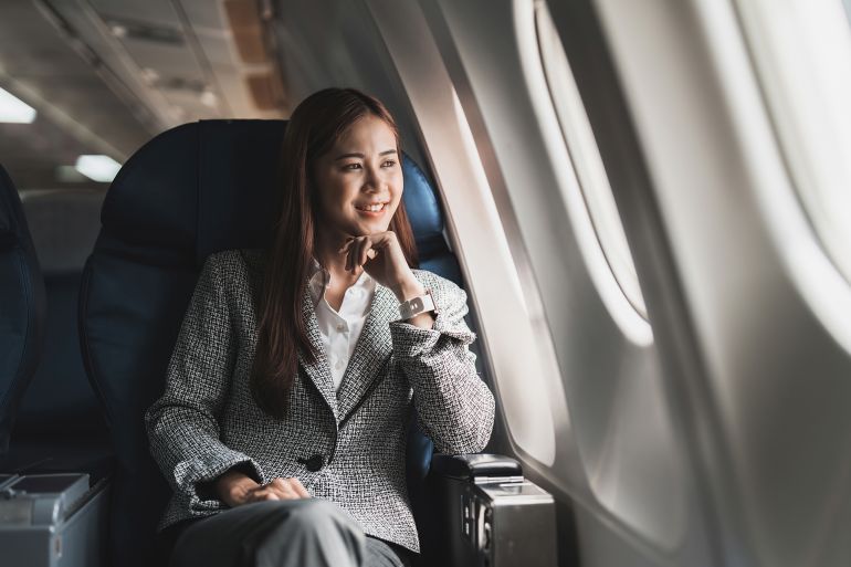 beautiful young asian woman sits in a plane and looking outside; shutterstock id 2168593341; purchase_order: aj; job: ; client: ; other: