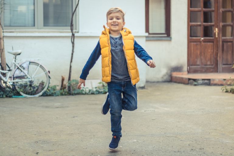 happy kid having fun and jumping on one leg outdoors. ; shutterstock id 1055514197; purchase_order: aj; job: ; client: ; other: