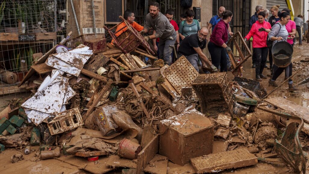 Mud-caked volunteers clean flood debris in a Spanish town as authorities struggle to respond