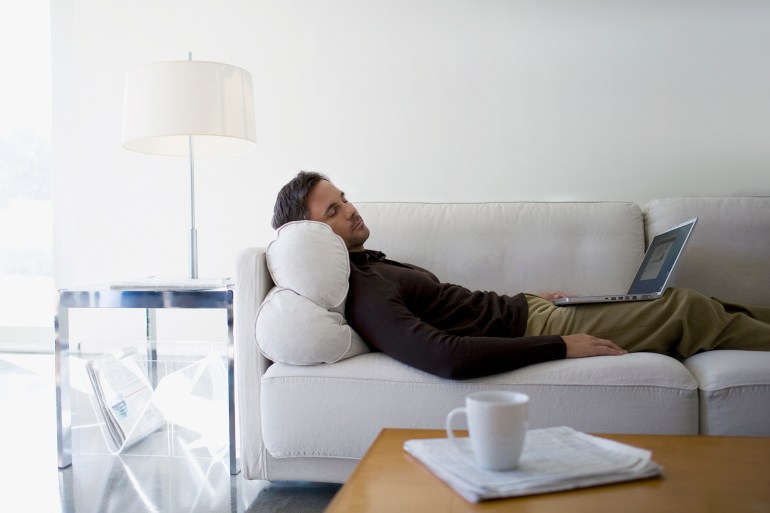 man with laptop sleeping on sofa - stock photo