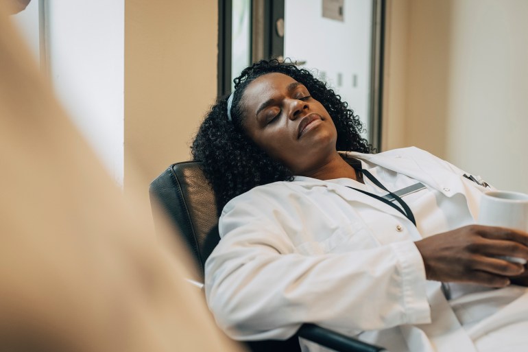 tired female doctor taking nap during coffee break in hospital - stock photo