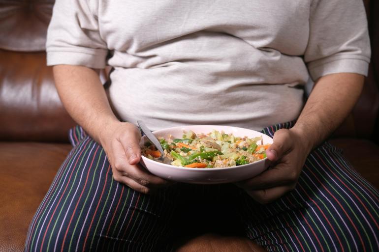 person holding a bowl of food with spoon