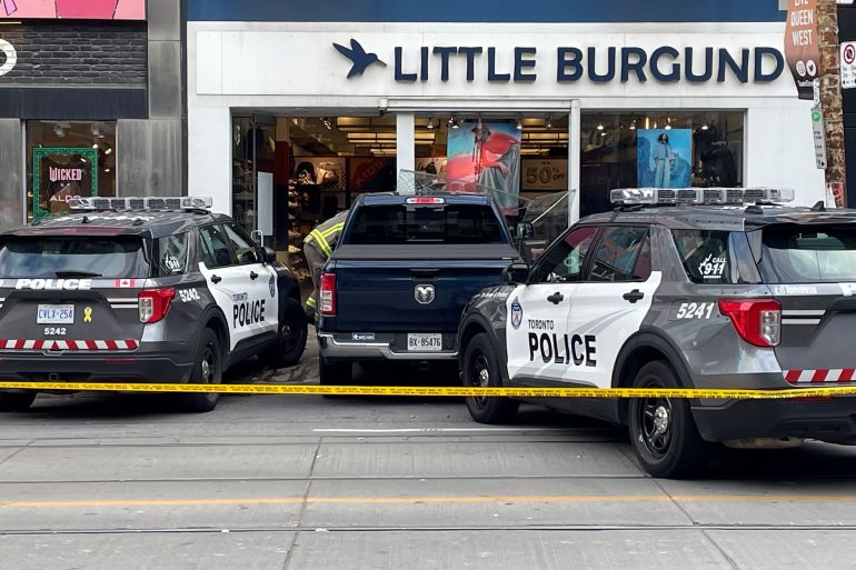 police officers pursue one person who jumped out of an alleged stolen truck that crashed into a downtown toronto store. credit : cp24