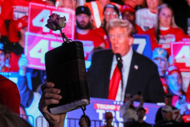 a supporter holds a bible and a rose, as republican presidential nominee and former u.s. president donald trump holds his campaign rally at macomb community college in warren, michigan, u.s., november 1, 2024. reuters/brian snyder