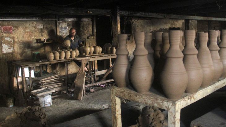 A person works on pots as Palestinians respond to an increase in the demand for clay pots used to cool water due to power cuts and hot weather, according to workers, amid the Israel-Hamas conflict, in Gaza City August 13, 2024. REUTERS/Mahmoud Issa