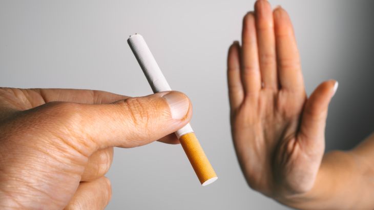 Woman showing stop sign with hand and refusing to take cigarette. No smoking or quit smoking concept