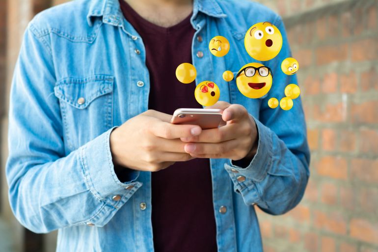 Close-up of man using smartphone sending emojis. Social concept.; Shutterstock ID 1408775138; purchase_order: aljazeera ; job: ; client: ; other: