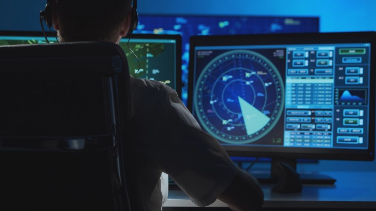 Workplace of the professional air traffic controller in the control tower. Caucasian aircraft control officer works using radar, computer navigation and digital maps. Aviation concept.