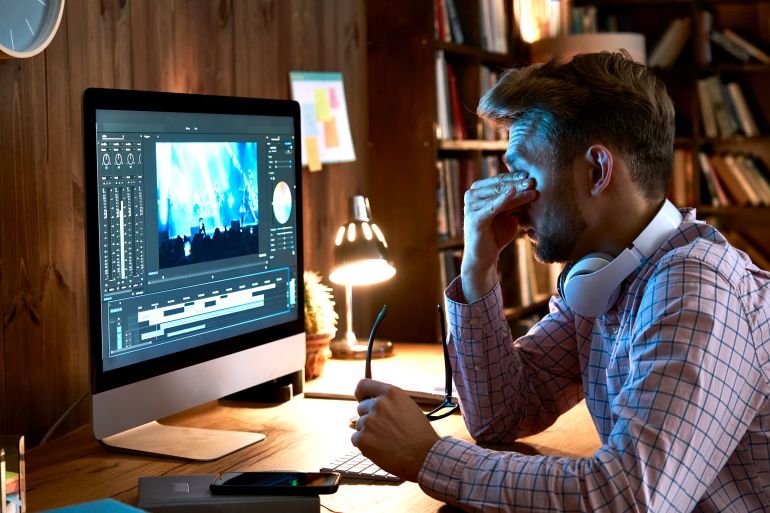 Tired overworked young business man taking off glasses rubbing tired dry eyes after long pc computer ...