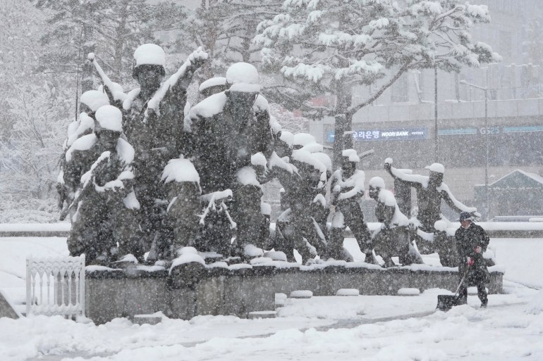 A worker shovels snow near a monument in remembrance of the Korean War at the Korea War Memorial Museum in Seoul Wednesday, Nov. 27, 2024. (AP Photo/Ahn Young-joon)