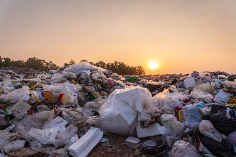 Close up large garbage pile near the sunset, global warming