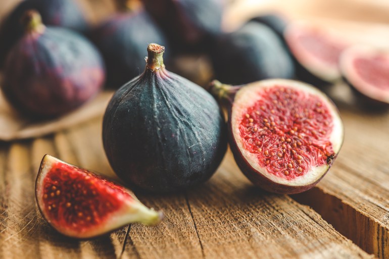 A few figs in a bowl on an old wooden background.