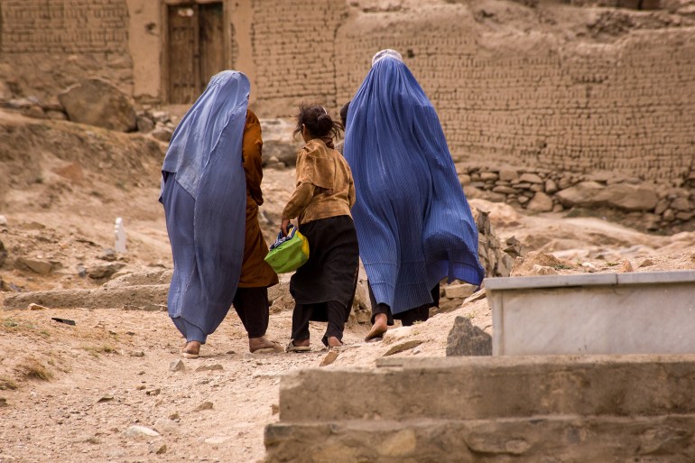 Girls and women in burqas walk through a graveyard near Kabul, Afghanistan; Shutterstock ID 574230577; purchase_order: aj; job: ; client: ; other: