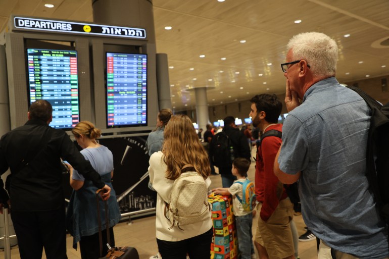 Passengers look at a departure board at Ben Gurion Airport near Tel Aviv, Israel, on October 7, 2023, as flights are canceled because of the Hamas surprise attacks. The conflict sparked major disruption at Tel Aviv airport, with American Airlines, Emirates, Lufthansa and Ryanair among carriers with cancelled flights. (Photo by GIL COHEN-MAGEN / AFP)