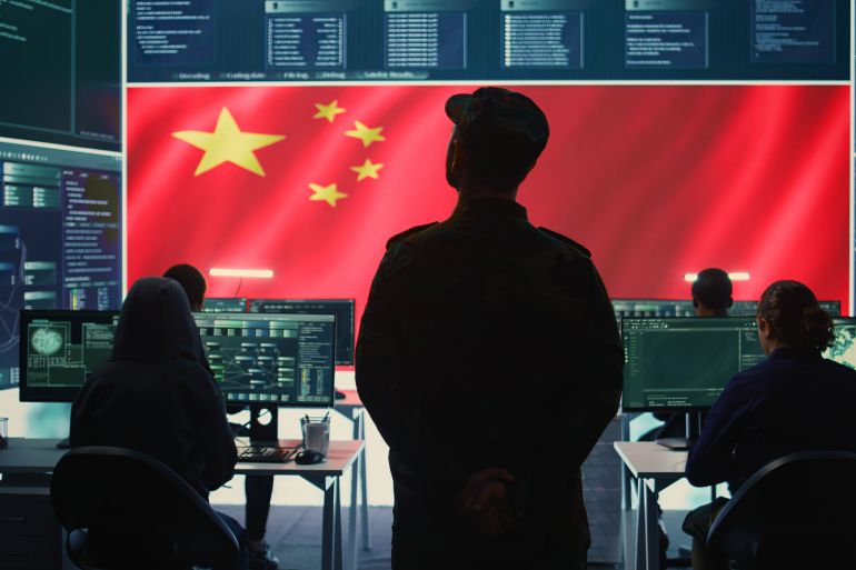 Chinese military personnel in a high tech government hacking room work on stealing state secrets from rival countries in hybrid war. Chinese army exploit advanced technology, inflict fear. Camera B.