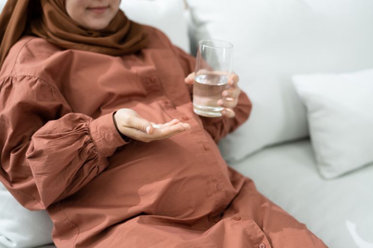 Pregnant Muslim Woman Taking Folic Acid Pill And Vitamins