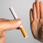 Woman showing stop sign with hand and refusing to take cigarette. No smoking or quit smoking concept