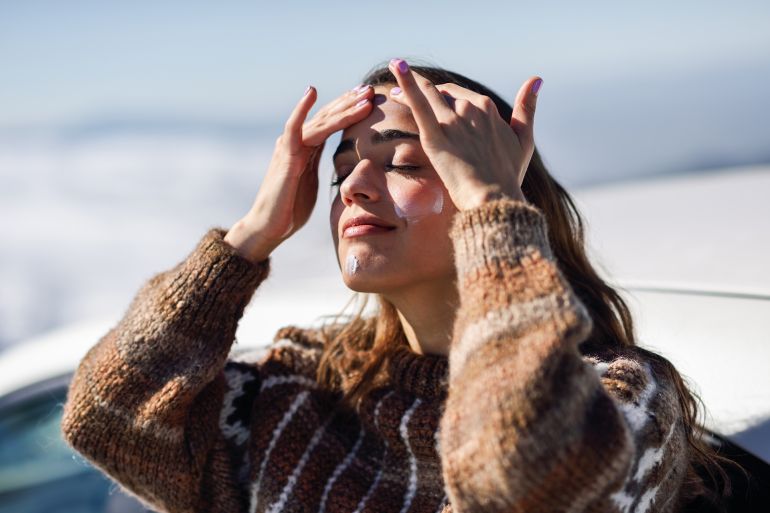 Young woman applying sunscreen on her face in snowy mountains in winter, in Sierra Nevada, Granada, Spain. Female wearing winter clothes.; Shutterstock ID 1516973336; purchase_order: aj; job: ; client: ; other: