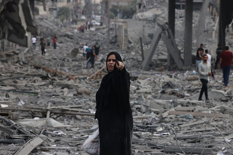 Palestinians walk through debris amid the destruction from Israeli airstrikes in Gaza City's al-Rimal neighbourhood on October 10, 2023. Israel kept up its deadly bombardment of Hamas-controlled Gaza on October 10 after the Palestinian militant group threatened to execute some of the around 150 hostages it abducted in a weekend assault if air strikes continue without warning. (Photo by MOHAMMED ABED / AFP)